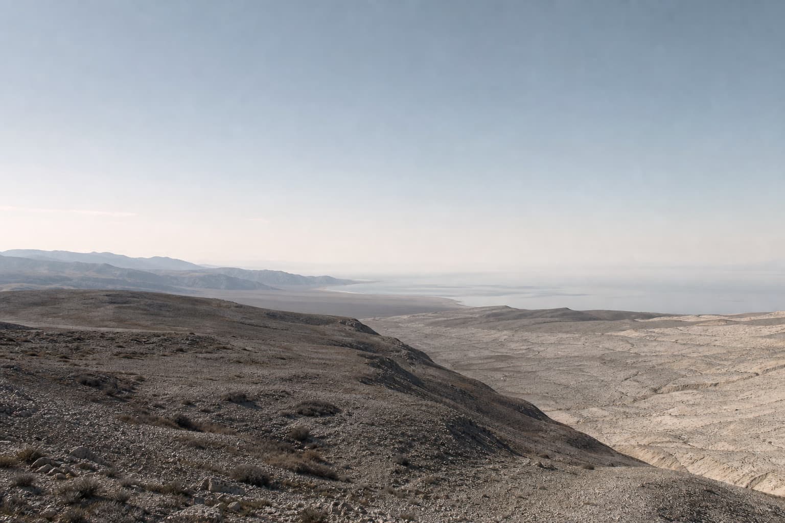 A restrained route crossing layered dunes toward a distant global horizon.