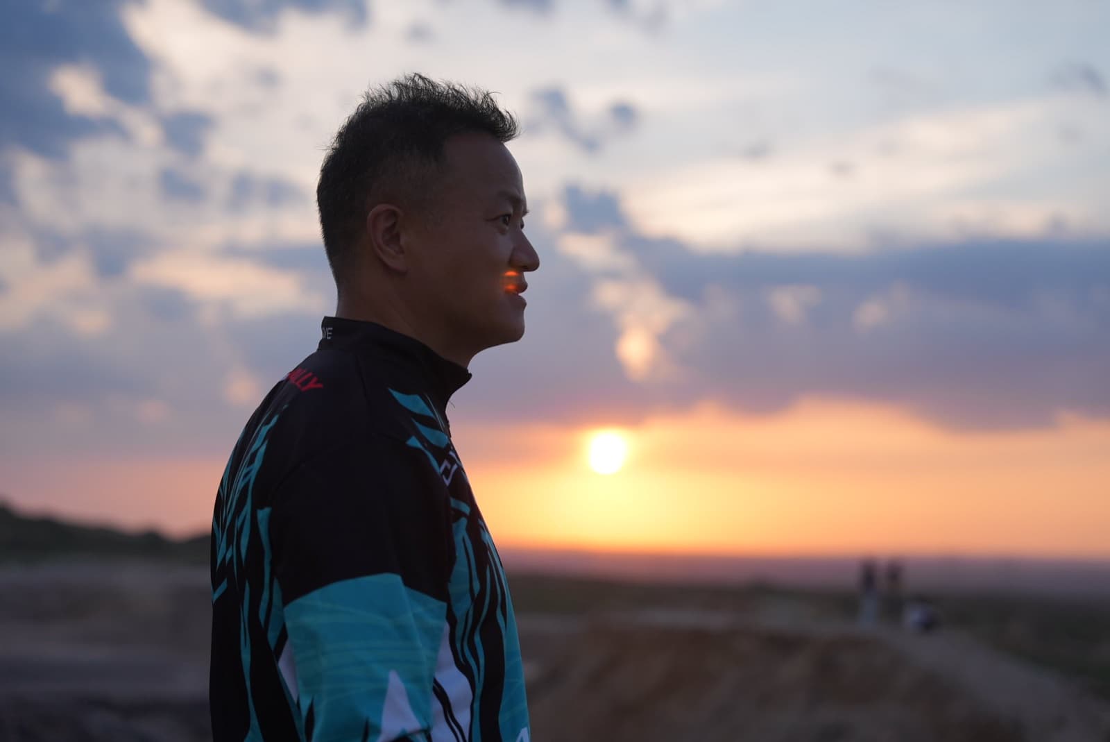 James TJ Lee in side profile at sunset, wearing field equipment.